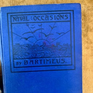 May include: A blue book titled "Naval Occasions" by Bartimeus. The cover features a black framed illustration of the sun rising over the ocean with birds flying above. The book's cover is a solid blue color.