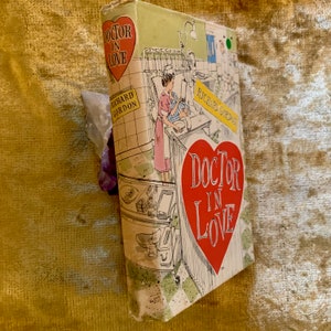 May include: A vintage paperback book titled "Doctor in Love" by Richard Gordon. The cover features a red heart with the title in white lettering and a cartoon illustration of a nurse in a hospital setting.