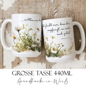 Könnte beinhalten: Zwei weiße Keramikbecher mit einem Blumendesign aus weißen Gänseblümchen und grünen Blättern. Die Becher haben gebogene Griffe und deutschen Text. Die Becher haben ein Fassungsvermögen von 440 ml.