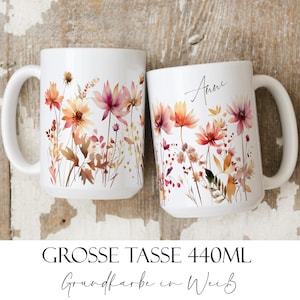 Può includere: Due tazze in ceramica bianca con un design floreale in tonalità arancio, rosa e marrone. La tazza a destra ha il nome "Anne" scritto su di essa. Entrambe le tazze hanno il testo "GROSSE TASSE 440ML Grundfarbe in Weiss" in basso.