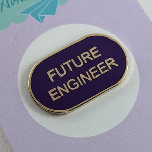 Peut inclure: Épinglette en émail dorée et violette avec le texte "FUTURE ENGINEER" sur fond blanc.