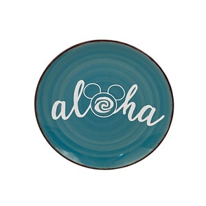 May include: A teal ceramic plate with a brown rim and the word "aloha" in white script. The "o" in "aloha" is replaced with a Mickey Mouse head design. The plate has a spiral pattern.
