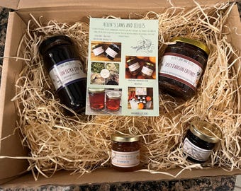 May include: A cardboard gift box filled with wood shavings containing four glass jars of preserves and a central informational card titled Helen's Jams and Jellies. The jars include Damson Extra Jam, Spicy Damson Chutney, and two smaller jars.