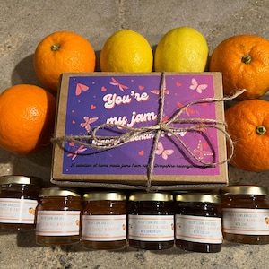 May include: A gift set with a box reading "You're my jam", surrounded by oranges, lemons, and jars of jam. The box is tied with twine. The jars have labels with text.