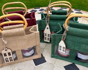 May include: Four small rectangular burlap gift bags with rounded wooden handles. The bags come in tan, burgundy, and two shades of green. Each bag features a clear plastic window at the bottom and a small wooden house-shaped gift tag.