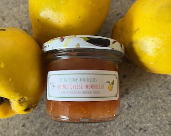 May include: A glass jar of quince cheese-membrillo, a type of fruit preserve, with a white label that reads "Helen's Jams and Jellies Quince Cheese-Membrillo Made with handpicked Shropshire quinces". The jar is surrounded by four yellow quince fruits.