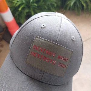 May include: Gray baseball cap with a green patch that reads "DESTROY WHAT DESTROYS YOU" in red lettering.