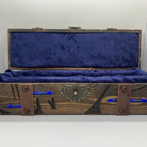 May include: A wooden box with a blue velvet interior and a metal latch. The box has a distressed wood finish and is decorated with metal accents. The box is lit from within with blue LED lights.