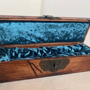 May include: A wooden box with a hinged lid and a blue velvet interior. The box has a decorative metal clasp with a heart design.