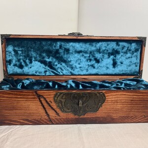 May include: A wooden box with a teal velvet lining and a metal latch. The box is closed and the lid is open.