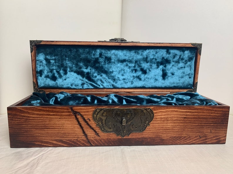 May include: A wooden box with a teal velvet lining and a metal latch. The box is closed and the lid is open.