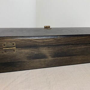 Pode incluir: Uma caixa de madeira escura com dobradi&ccedil;as de lat&atilde;o e um fecho de lat&atilde;o. A caixa tem um padr&atilde;o de gr&atilde;o de madeira natural.