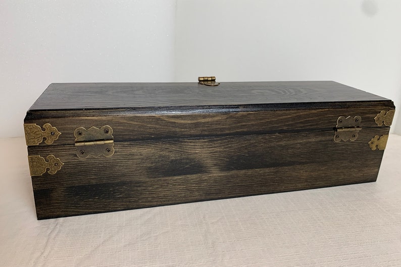 Pode incluir: Uma caixa de madeira escura com dobradi&ccedil;as de lat&atilde;o e um fecho de lat&atilde;o. A caixa tem um padr&atilde;o de gr&atilde;o de madeira natural.