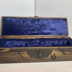 K&ouml;nnte beinhalten: Eine Holzkiste mit einer dunkelbraunen Beize und einer blauen Samtf&uuml;tterung. Die Kiste hat einen Metallverschluss und dekorative Metallakzente.