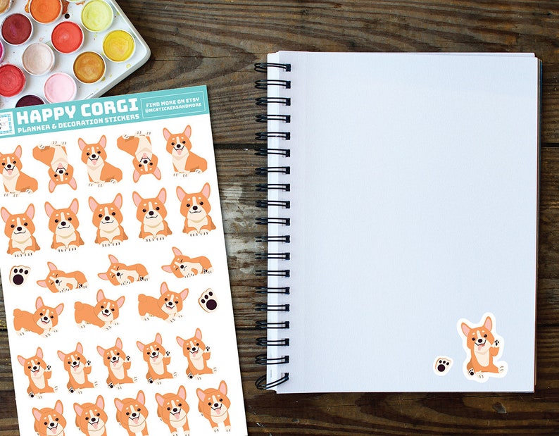 Puede incluir: Una hoja de pegatinas con una variedad de adorables corgis de dibujos animados en diferentes poses. Las pegatinas est&aacute;n etiquetadas como "Happy Corgi Planner & Decoration Stickers".