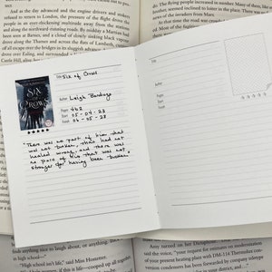 May include: A close-up of a book journal with a white cover and black lines. The journal has a section for recording book details, including the title, author, pages, start date, and finish date. The book title is "Six of Crows" by Leigh Bardugo. The journal has a five-star rating.
