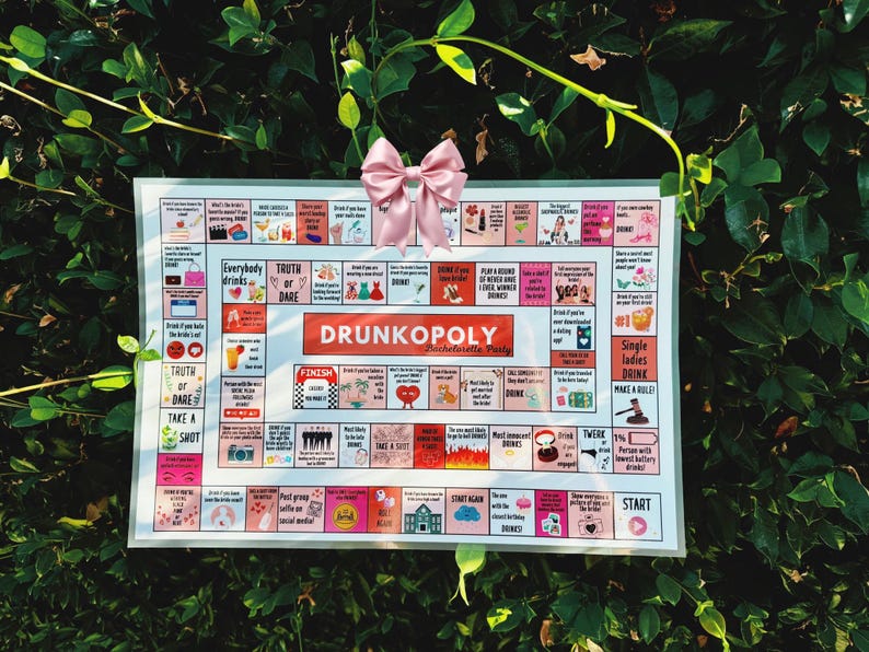 May include: A white game board with the title "Drunkopoly:  Parcheesi-style Party" printed in red and black. The board features squares with various prompts for drinking games, such as "Truth or Dare", "Take a Shot", and "Everybody Drinks".
