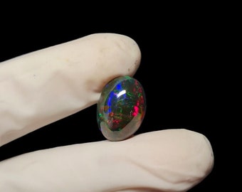 May include: A dark oval-shaped black opal gemstone with flashes of green, blue, and red.