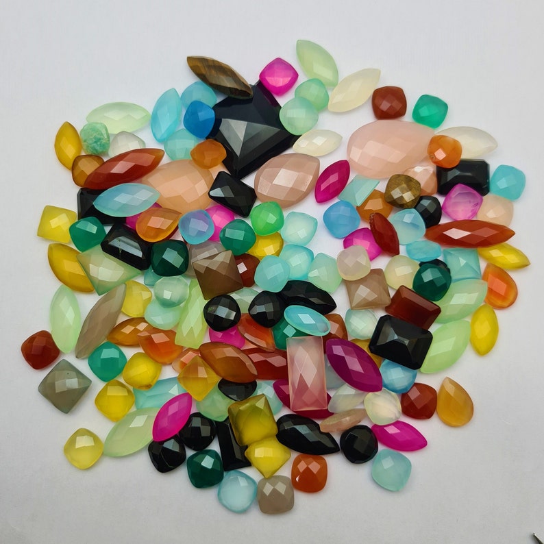 Puede incluir: Una gran colecci&oacute;n de cabujones de piedras preciosas de colores en varias formas y tama&ntilde;os. Los cabujones son una mezcla de piedras opacas y transl&uacute;cidas, incluyendo verde, azul, rojo, rosa, amarillo y marr&oacute;n.