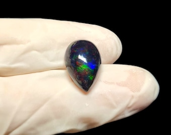 May include: A teardrop-shaped black opal gemstone with iridescent green, blue, and red flashes.