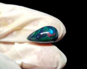 May include: A teardrop-shaped green, blue, and red opal gemstone.