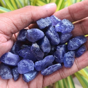 May include: A collection of small, rough, blue-purple gemstone chips. The chips are various sizes and shapes, and have a natural, unpolished look.