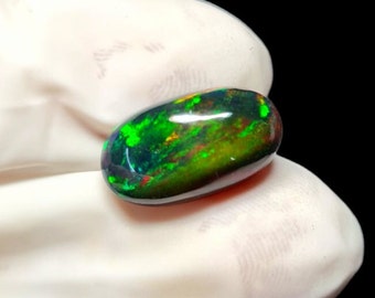 May include: A dark green, black, and red oval-shaped opal gemstone with iridescent flashes of color.