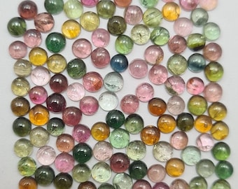 May include: A collection of round, multi-colored gemstones. The gemstones are various shades of green, pink, yellow, and blue. The gemstones are arranged in a square shape on a white background.