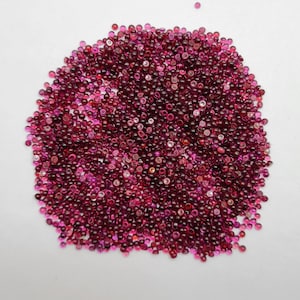 Puede incluir: Un montón grande de pequeñas piedras preciosas redondas de color rojo. Las piedras preciosas son todas de aproximadamente el mismo tamaño y tienen un acabado brillante y pulido.