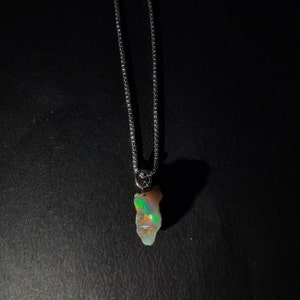 Op de afbeelding: Een zilveren ketting met een hanger met een ruwe, iriserende opaal.
