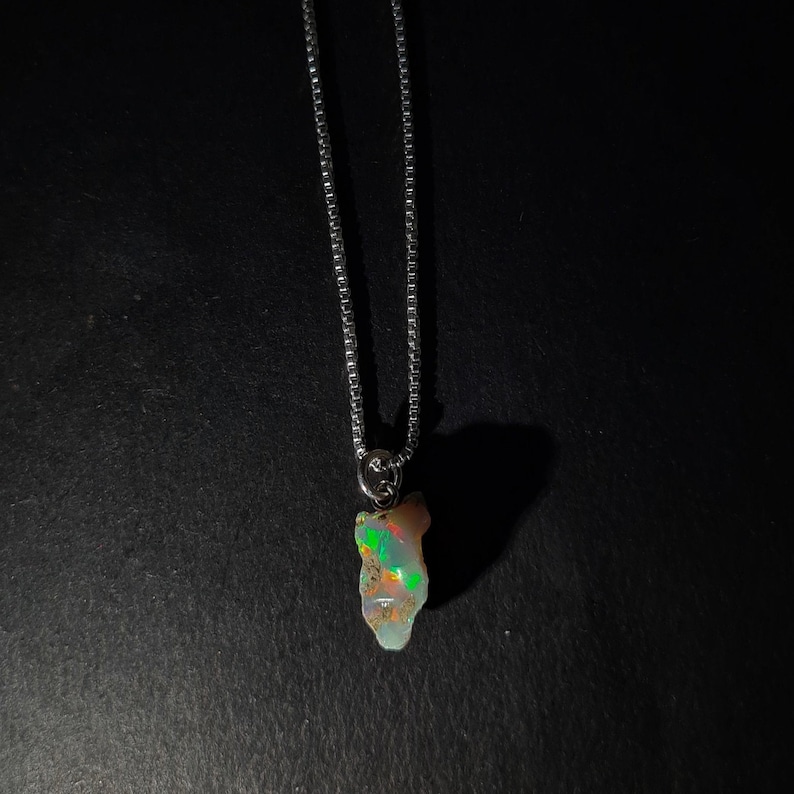 Op de afbeelding: Een zilveren ketting met een hanger met een ruwe, iriserende opaal.