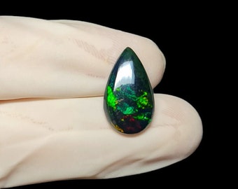 May include: A teardrop-shaped black opal gemstone with green, red, and yellow flashes of color.