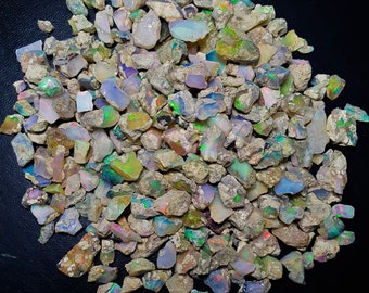 May include: A collection of rough, iridescent opal gemstones in various sizes and shapes. The opals are a mix of white, grey, and brown with flashes of green, blue, and pink.
