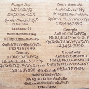 Puede incluir: Una superficie de madera clara muestra ejemplos grabados de varias fuentes, incluyendo Freestyle Script, Comic Sans MS, Bauhaus 93, Georgia, Century, Broadway y Old English. Cada fuente muestra el alfabeto y los n&uacute;meros.
