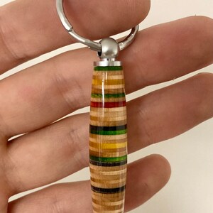 May include: A colorful wooden keychain with a silver key ring. The keychain is made from layered wood with stripes of red, yellow, green, and blue.