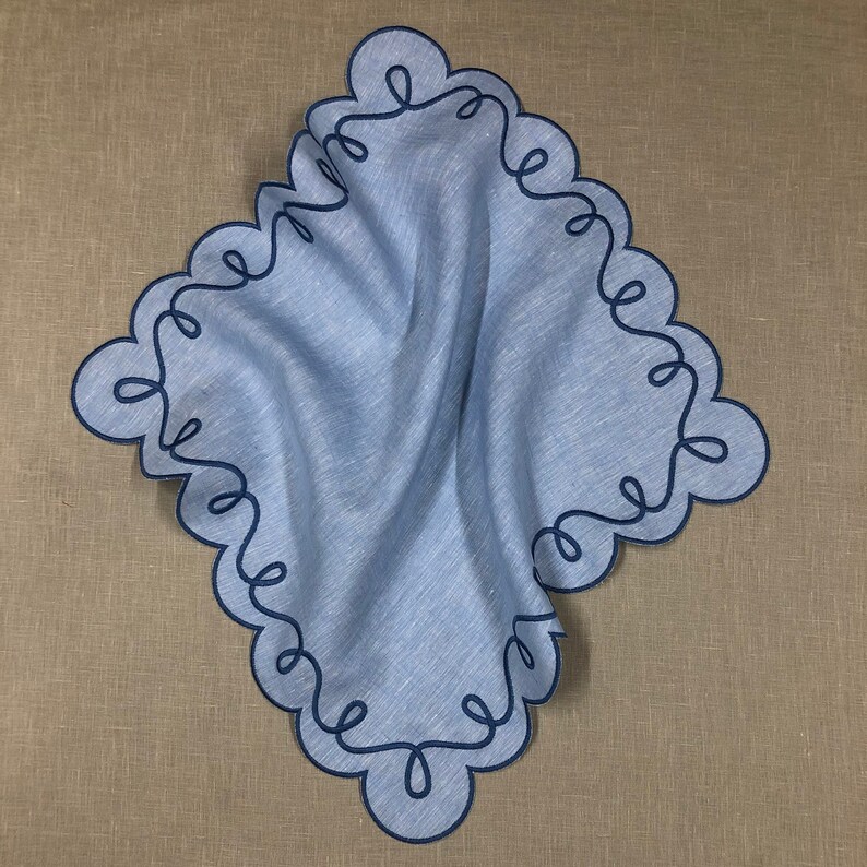 May include: A light blue linen handkerchief with a decorative blue embroidered scalloped edge.