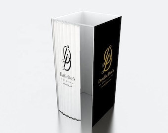 May include: A white and black display booth with the text "Double Dee's Lingerie" in a stylized font. The booth has a white curtain and a black panel with a gold logo. The booth is designed for displaying lingerie.