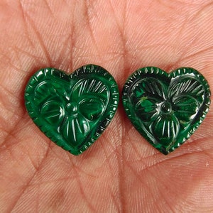 Puede incluir: Dos colgantes de piedra preciosa tallados en forma de corazón verde con un diseño floral.