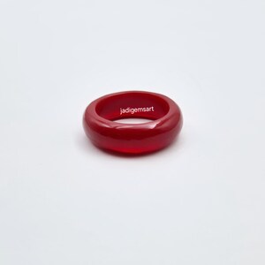 May include: A vibrant red ring with a smooth, polished surface. The ring is a solid band of color, with the text "jadigemsart" printed on the surface. The ring is set against a plain white background.
