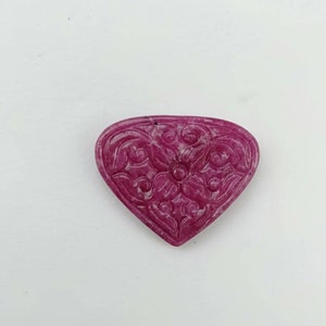 May include: A carved pink heart-shaped gemstone pendant with a floral design.