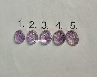 Könnte beinhalten: Fünf ovale Amethyst-Edelsteine mit geschnitzten Blumenmustern. Jeder Stein hat einen anderen Farbton von Lila, von hellem Lavendel bis zu tiefem Violett. Die Edelsteine sind mit 1 bis 5 nummeriert.