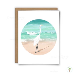 An A2 sized greeting card that features a spot illustration of a Great Egret on the beach near the shoreline