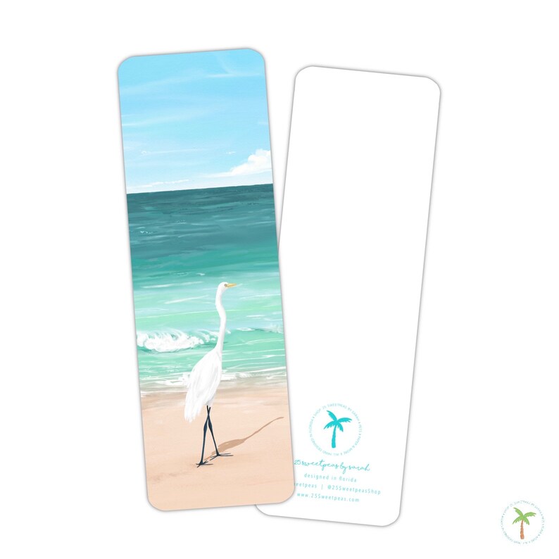 A thick laminated bookmark featuring an illustration print of a Great Egret on the beach, the perfect bookmark for your next beach read