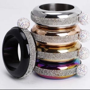 May include: A set of five different coloured metal bracelets with a rhinestone design. Each bracelet has a round, clear rhinestone ball on the side.