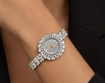 May include: A silver-toned wristwatch featuring a round dial surrounded by a halo of marquise-cut clear stones. The bracelet is composed of multiple rows of marquise-cut stones, creating a continuous sparkling effect around the wrist.