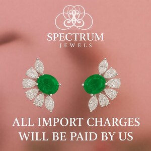 May include: A pair of gemstone earrings with a central oval emerald surrounded by white pear-shaped diamonds. The earrings are set against a pink background with the text "SPECTRUM JEWELS" and "ALL IMPORT CHARGES WILL BE PAID BY US".