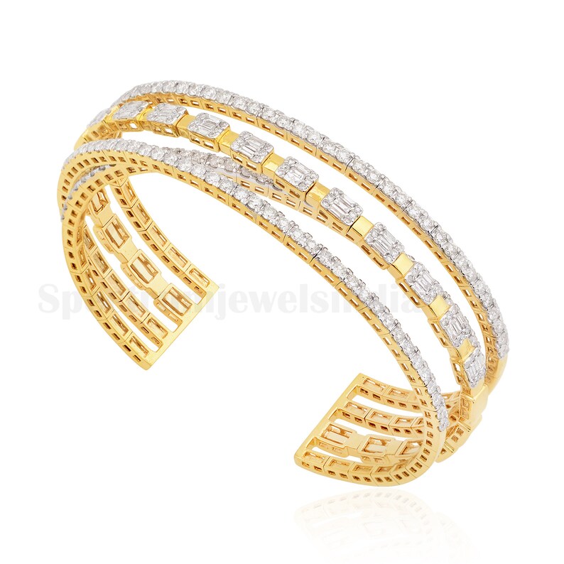 May include: A gold-toned cuff bracelet with three parallel bands. Each band is encrusted with small, sparkling diamonds. The center band features rectangular diamond accents. The bracelet has an open design.