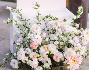 May include: A white pedestal with a floral arrangement of white and peach flowers. The arrangement is approximately 2 feet long, 14-16 inches wide, and 16-20 inches tall.