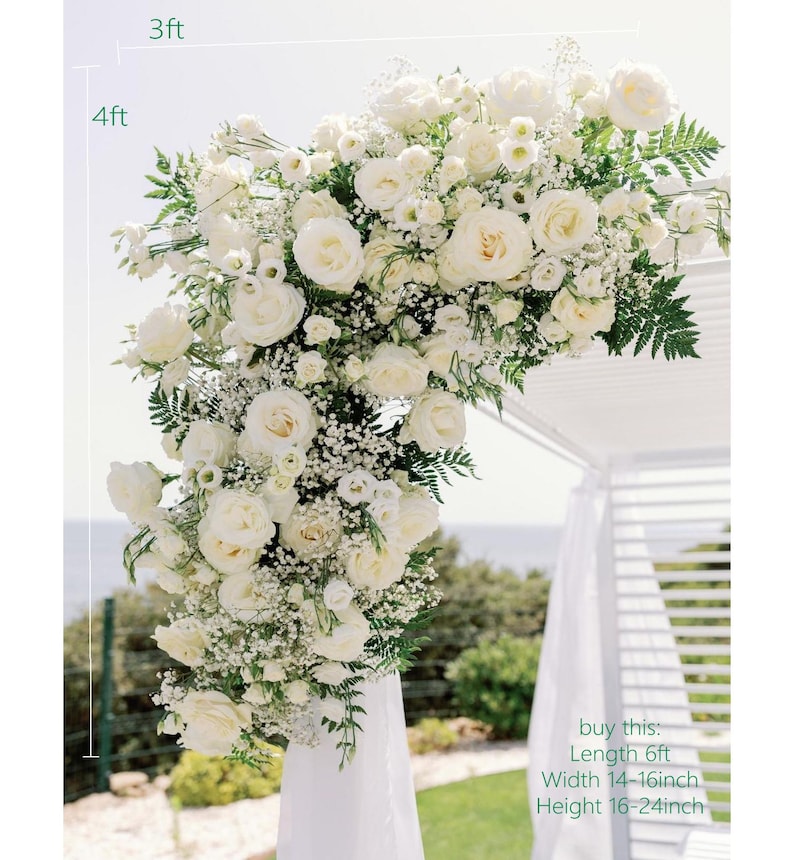 May include: A white floral archway, approximately 122 cm tall and 91 cm wide, decorated with white roses, baby's breath, and greenery. The archway has a cascade of flowers. The text on the image says: Length 6ft, Width 36-41cm, Height 41-61cm.
