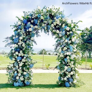 May include: A floral archway, 8 feet wide and 8 feet high, adorned with white roses, blue hydrangeas, and greenery. The arch is set on a green lawn with a blue sky background. Text on the image reads "ArchFlowers W8xH8 ft".